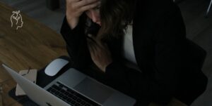 Jeune femme face à son ordinateur portable qui prend sa tête dans ses mains