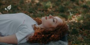 Femme allongée dans l'herbe et qui ferme les yeux