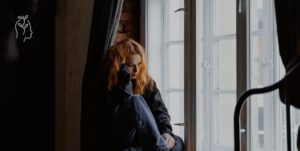 Jeune femme anxieuse assise à sa fenêtre