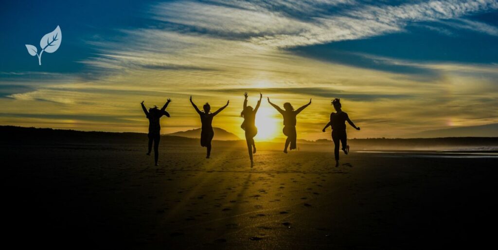 Bande d'amis en train de sauter en l'air face au coucher du soleil