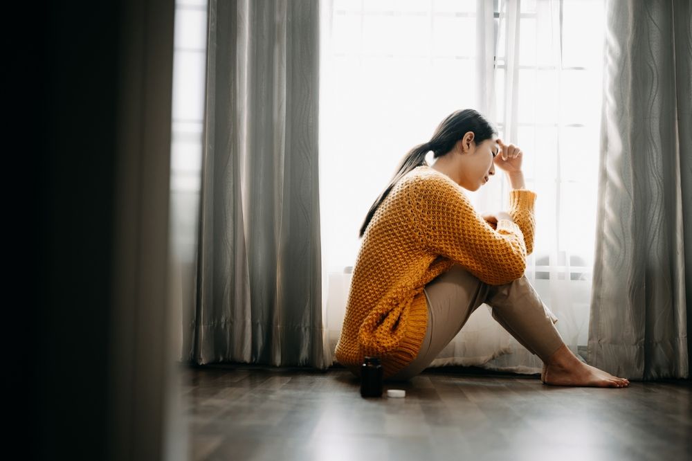 jeune femme asiatique assise par terre qui semble déprimée