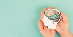 Mains tenant une tête en papier, cerveau humain avec des fleurs, concept de soins personnels et de santé mentale, pensée positive