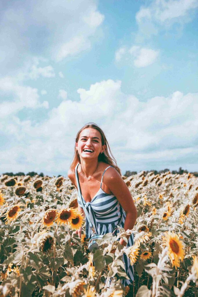 jeune fille blonde souriante dans un champ de tournesol